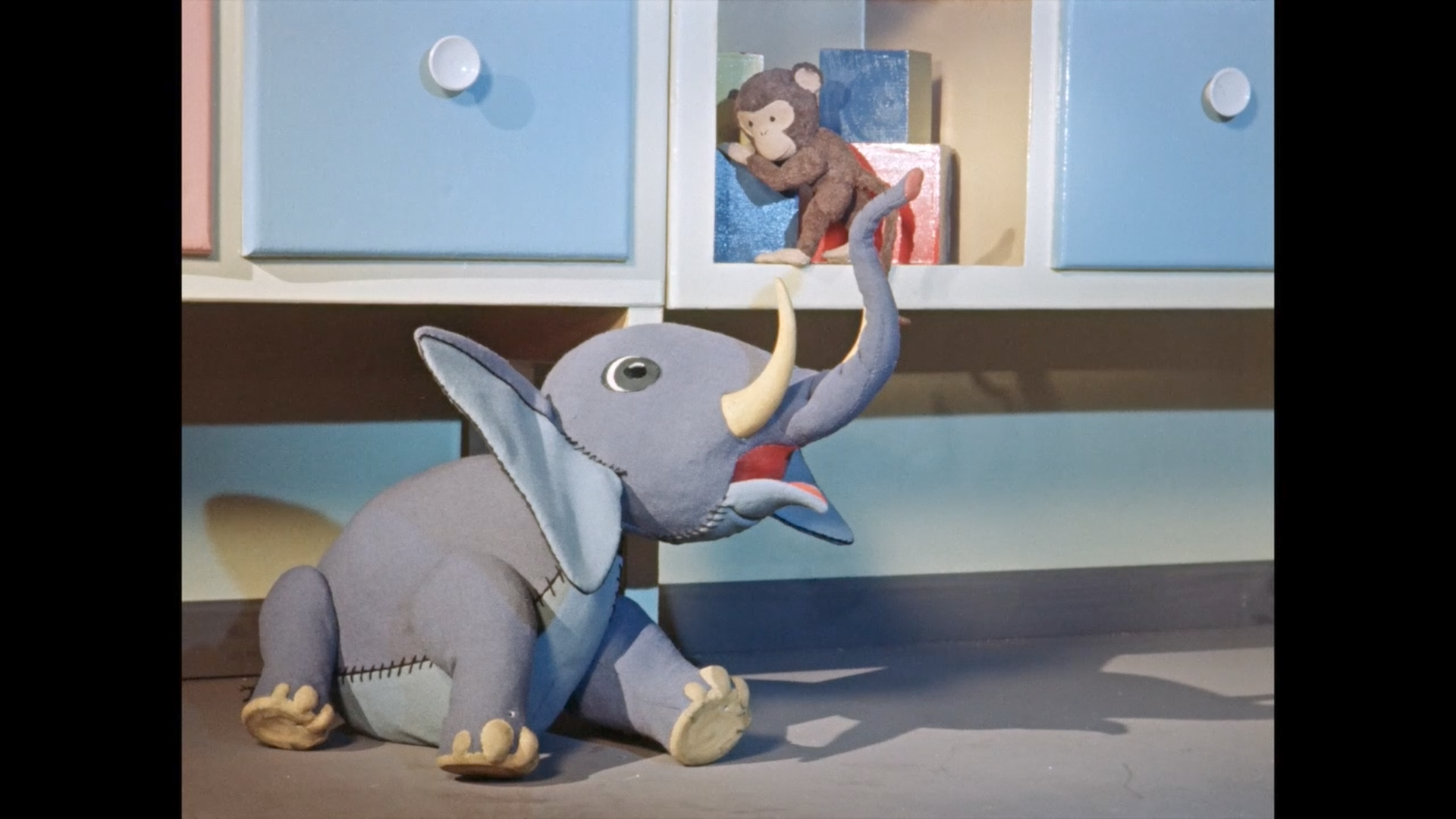 Der Elefant hebt den Affen zu einem Regal hinauf.